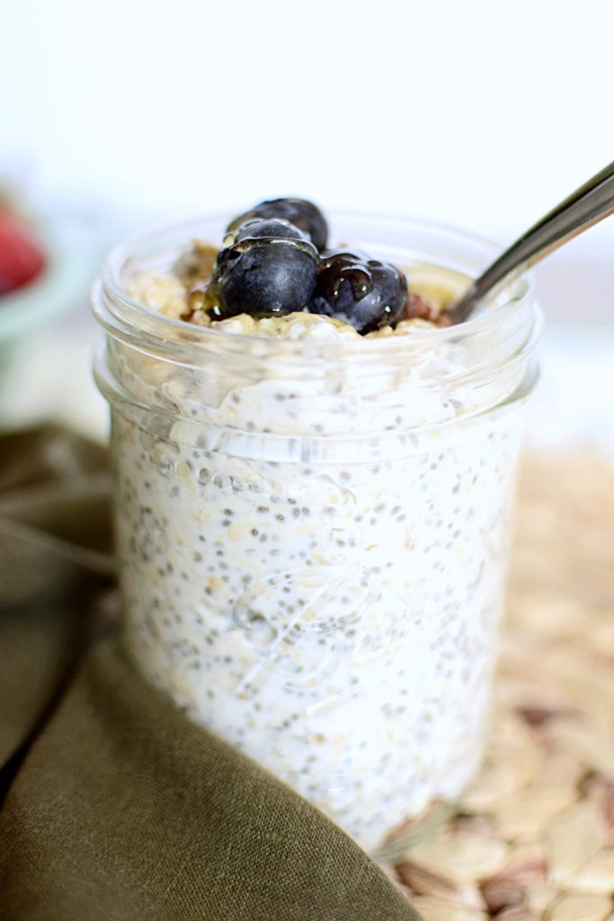 Overnight oats in a wide mouth mason jar topped with blueberries, granola and drizzled with honey